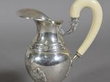 an antique silver plated pitcher with a horn handle and handle