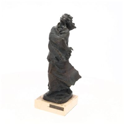 statue d'un homme portant un chapeau et une robe, posée sur un socle en bois