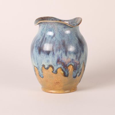 un vase bleu et jaune posé sur une surface blanche