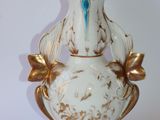 a white and gold vase with a blue bird on it
