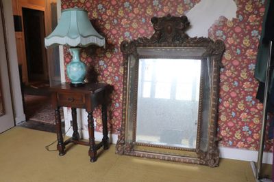 a mirror and a lamp in a room with a wallpapered wall