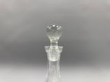 une carafe en verre posée sur une surface blanche, sur fond gris