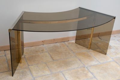 a glass table with a curved glass top on a tile floor