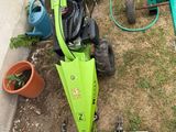 a green lawn mower sitting on the ground next to a lawn mower