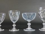 four clear glass goblets sitting next to each other on a table