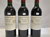 three bottles of red wine are lined up on a table