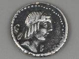 an ancient coin with a woman ' s head and a feather on it