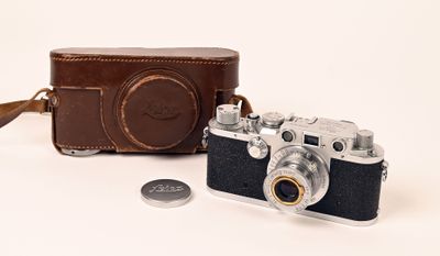 un petit appareil photo et une pièce de monnaie posés sur une surface blanche