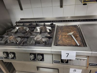 une cuisinière avec une casserole posée dessus, dans une cuisine