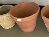 trois grands pots en argile posés les uns à côté des autres sur le sol