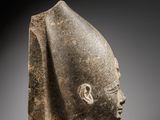 an ancient stone head of a man with a beard