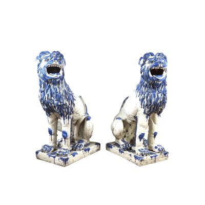 une paire de lions en porcelaine bleue et blanche sur des socles, sur fond blanc