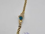 a close up of a gold bracelet with a blue stone on it