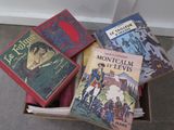 several books in a box sitting on the floor in front of a wall