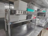 des plans de travail en acier inoxydable dans une cuisine professionnelle, sur lesquels sont posés de nombreux plats