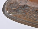 a bronze statue of a bird sitting on top of a leaf