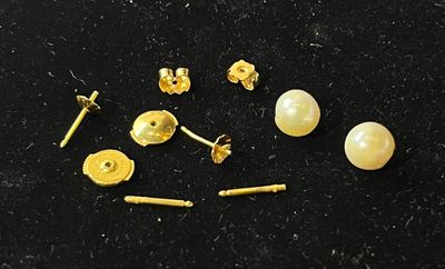 some gold studs and screws are laying on a black surface