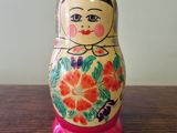 brightly colored matry doll sitting on a wooden table in front of a blackboard