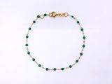 a gold chain bracelet with green glass beads on a white background