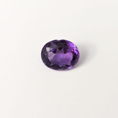 gros plan d'une pierre précieuse violette sur une surface blanche