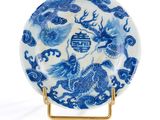 assiette bleue et blanche ornée d'un dragon, posée sur un socle doré