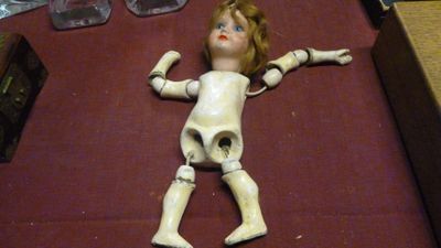 une poupée posée par terre à côté d'autres objets