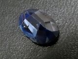 a close up of a faceted blue sapphire on a black surface
