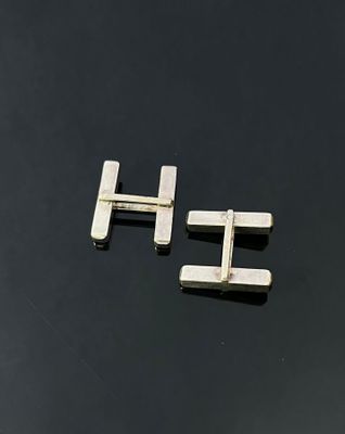 a pair of silver cufflinks on a black surface
