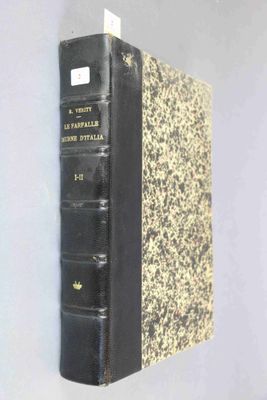 an old book with a black cover sitting on top of a white wall