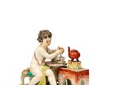 une figurine représentant un garçon assis à une table sur laquelle est posé un oiseau