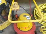 a red and yellow machine and a yellow hose on the ground