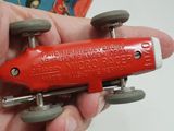 a person holding a red toy car in their hand