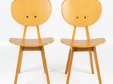 two wooden chairs sitting next to each other on a white surface
