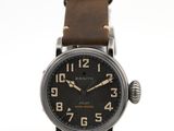 une photo d'une montre-bracelet avec un cadran noir et un bracelet en cuir marron