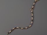 a close up of a gold and blue necklace on a gray surface