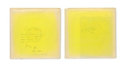 two pieces of yellow paper with writing on them on a white surface