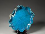 a close up of a blue plate on a stand on a gray surface