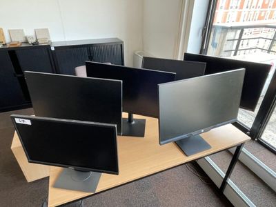 trois écrans d'ordinateur posés sur un bureau près d'une fenêtre