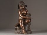 bronze statue of a boy sitting on a rock with a cat