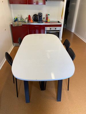 une table et des chaises blanches dans une cuisine aux placards rouges