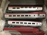 trois trains rouges et argentés se trouvent dans une boîte posée sur une table