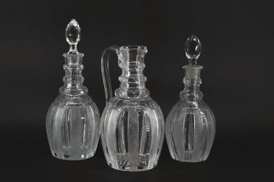 three clear glass decanters on a black surface with a black background