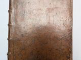 un vieux livre posé sur une table à côté d'un mur blanc