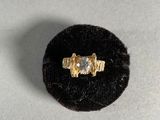 a gold ring with a diamond on top of a black velvet ring holder
