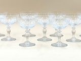 six verres à vin transparents sont alignés sur une surface blanche