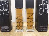two bottles of nars cosmetics sitting on a table next to each other