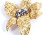gold tone flower brooch with blue and white stones in center