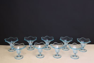 six blue glass vases sitting on top of a white table