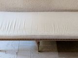 a bench with a white cushion on it in a room