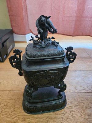 une statue en bronze représentant un oiseau perché sur un bol
